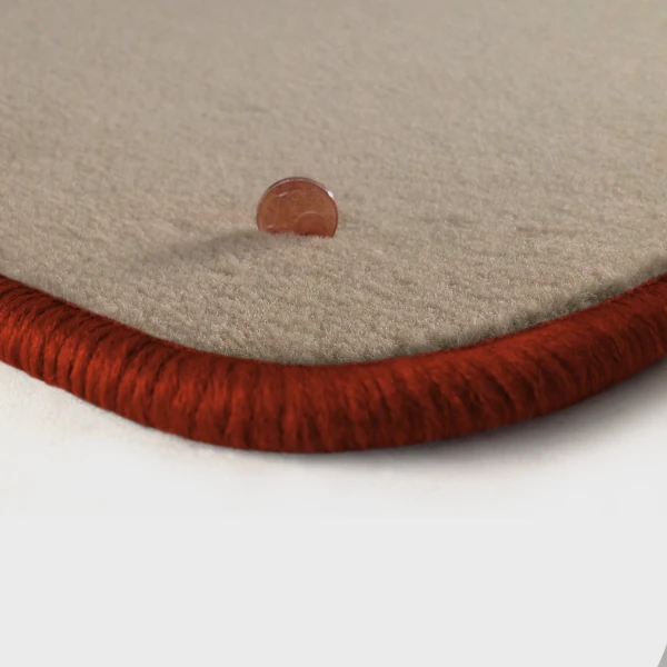 Eine Ecke als Beispiel einer Fussmatte Velours beige mit Rand in kupfer.