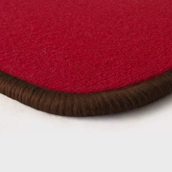 Eine Ecke als Beispiel einer Fussmatte Velours rot mit Rand in braun.