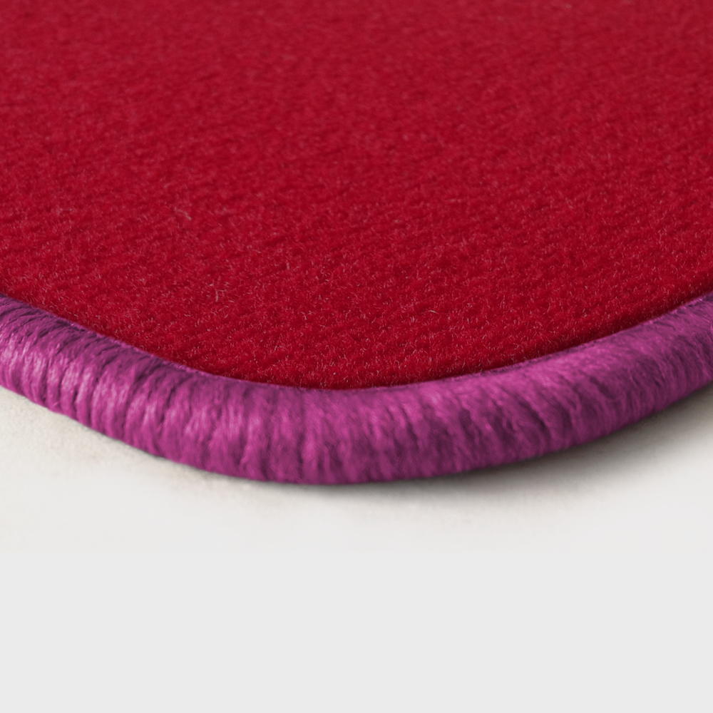 Eine Ecke als Beispiel einer Fussmatte Velours rot mit Rand in pink.