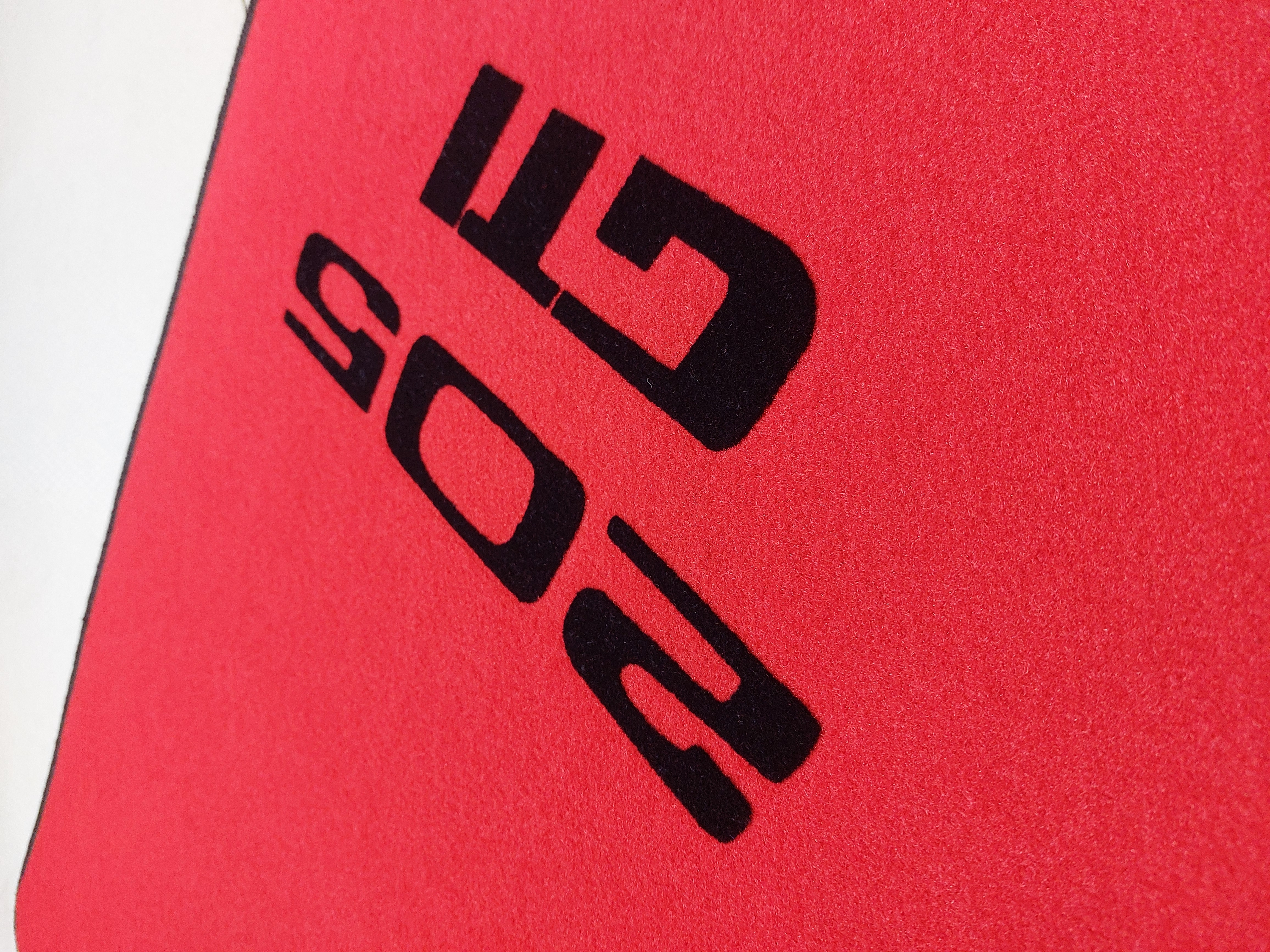 seitliches Peugeot 205 GTi Logo 1 Seitliche ansicht des Peugeot 205 Gti Logos auf rotem Velours und Druck in schwarz.1