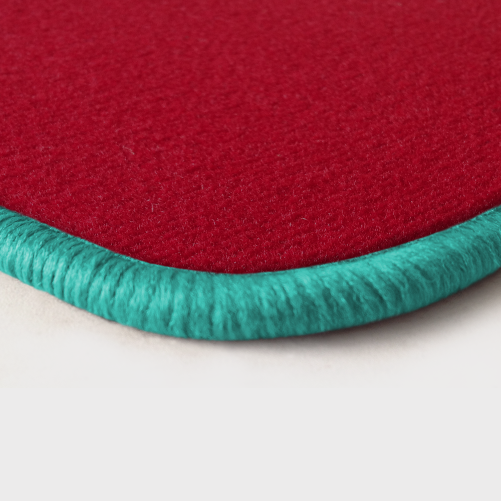 Eine Ecke als Beispiel einer Fussmatte Velours rot mit Rand in mint.
