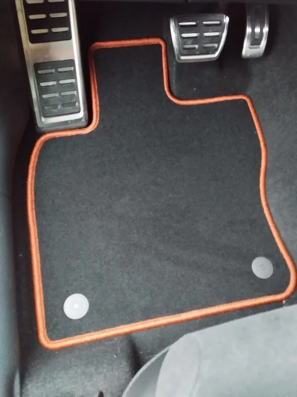 Blick in den Fahrerfußraum eines Cupra Ateca, in dem eine schwarze Fußmatte mit rotem Rand liegt.