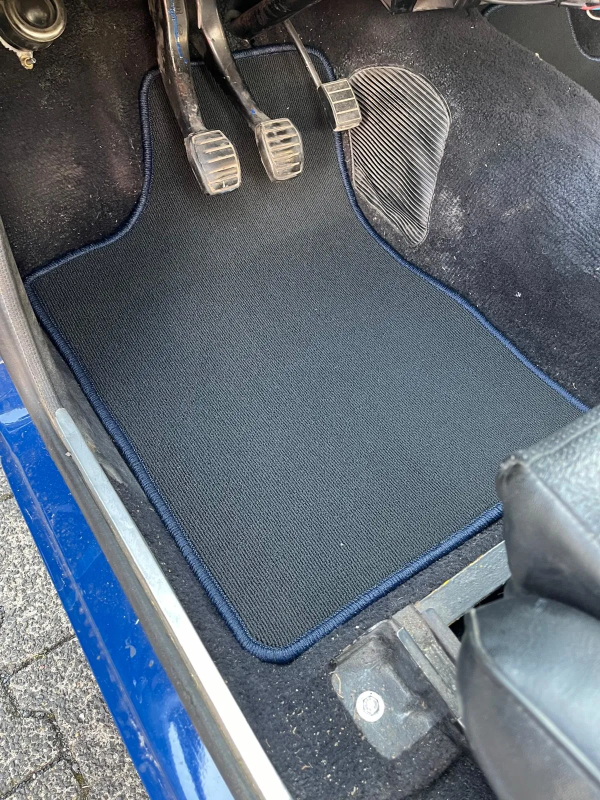 Blick in den Fahrerfußraum eines Ford Escort mit einer eingepassten Fußmatte