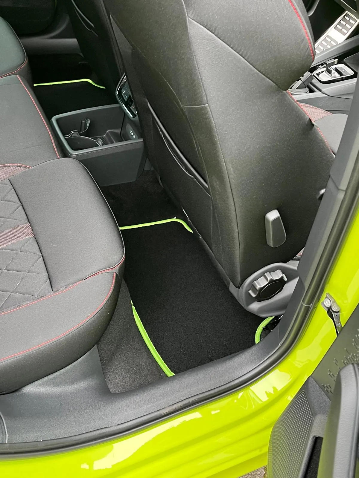 Blick in den Fond eines Skoda Octavia 4 RS, in dem eine schwarze Fußmatte mit neon-grünem Rand liegt