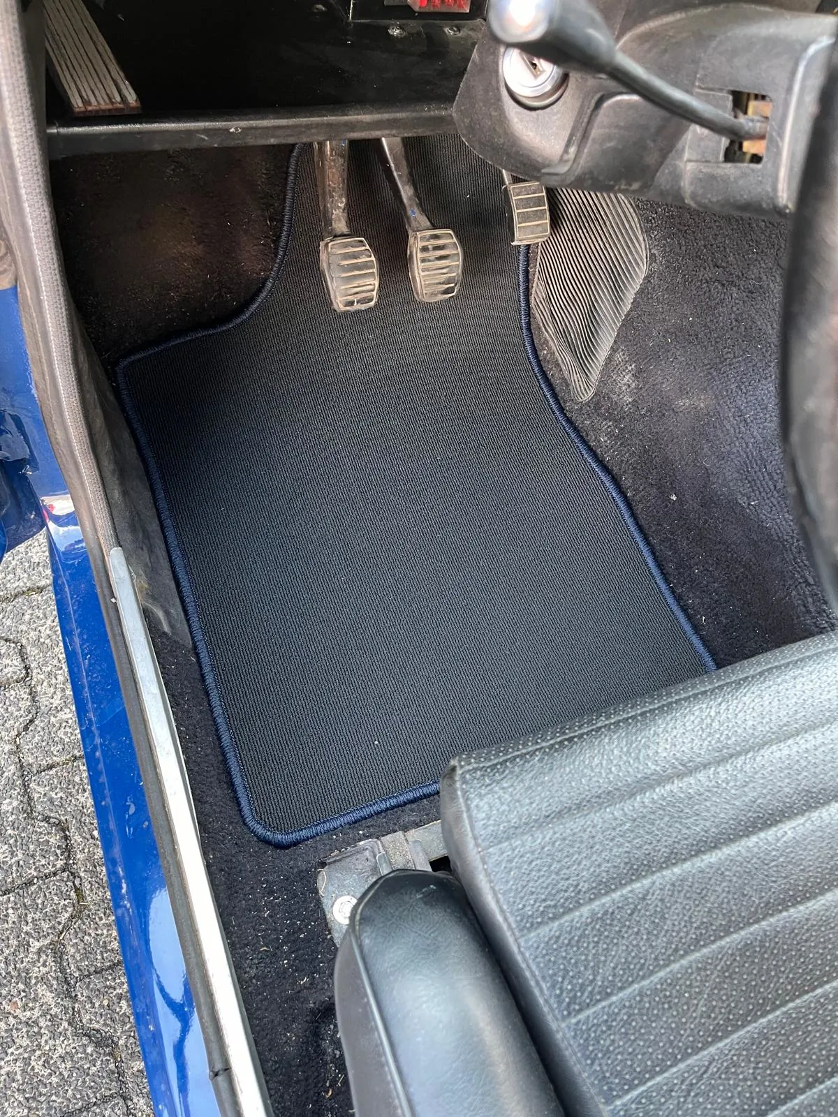 Blick in den Fahrerfußraum eines Ford Escort mit einer eingepassten Fußmatte