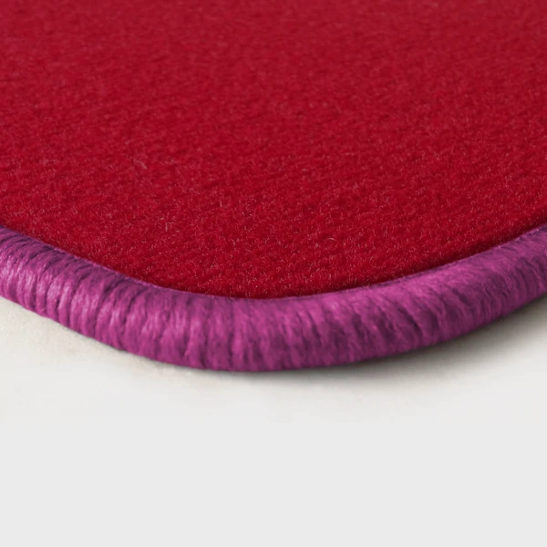 Eine Ecke als Beispiel einer Fussmatte Velours rot mit Rand in pink.