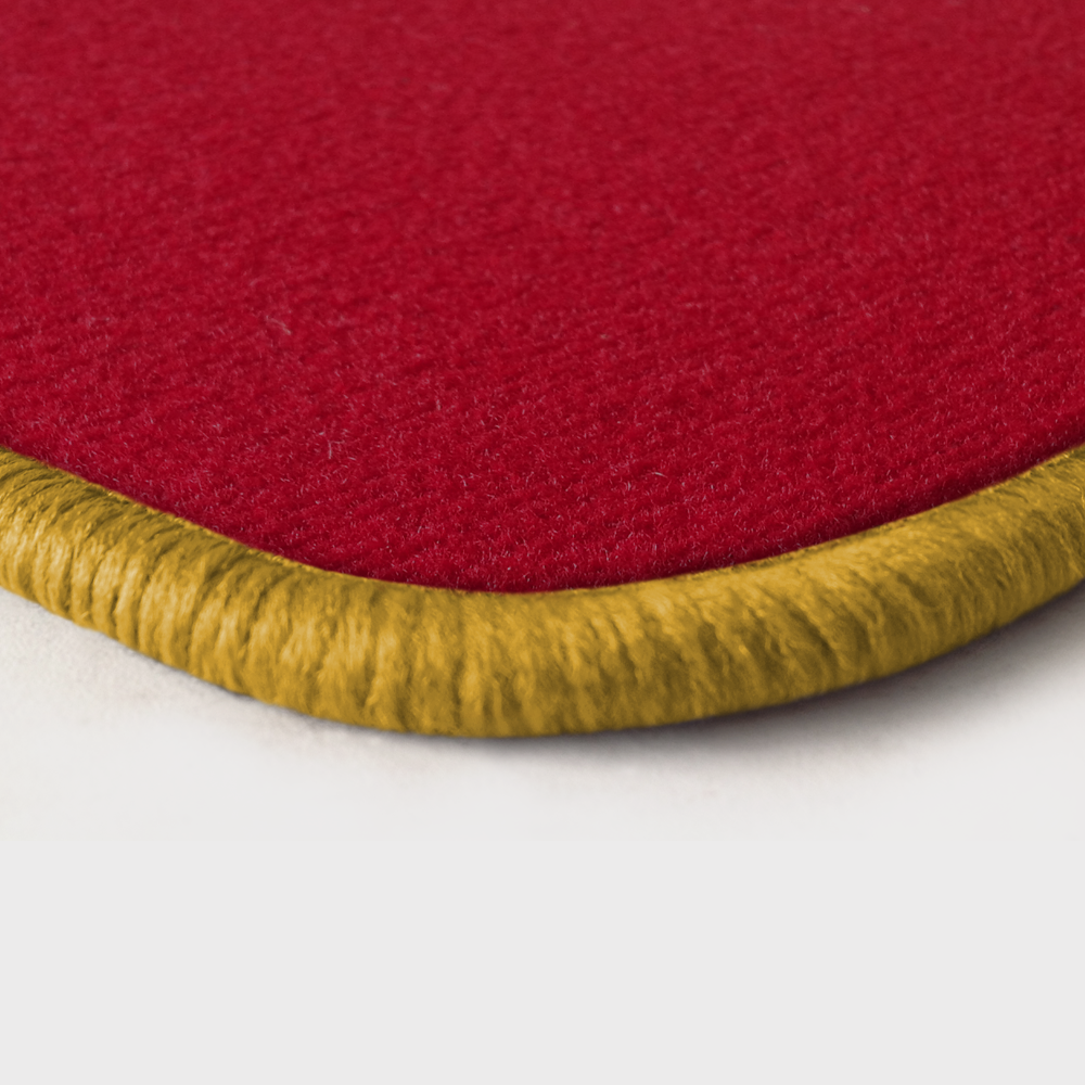 Eine Ecke als Beispiel einer Fussmatte Velours rot mit Rand in gelb.