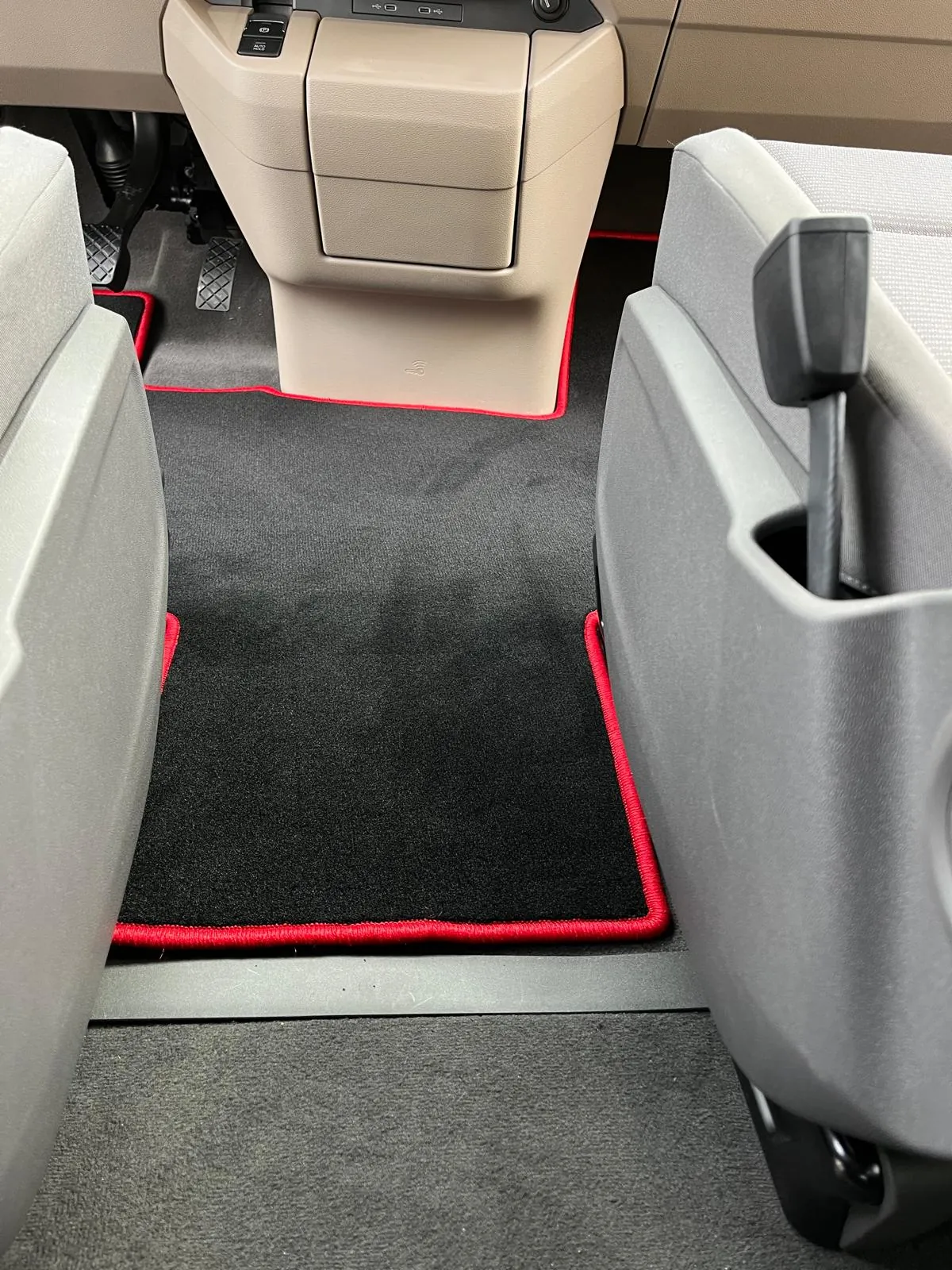 Blick in die Fahrerkabine eines VW T7 New Multivan 5, in der eine schwarze, perfekt eingepasste Fußbodenmatte mit rotem Rand liegt